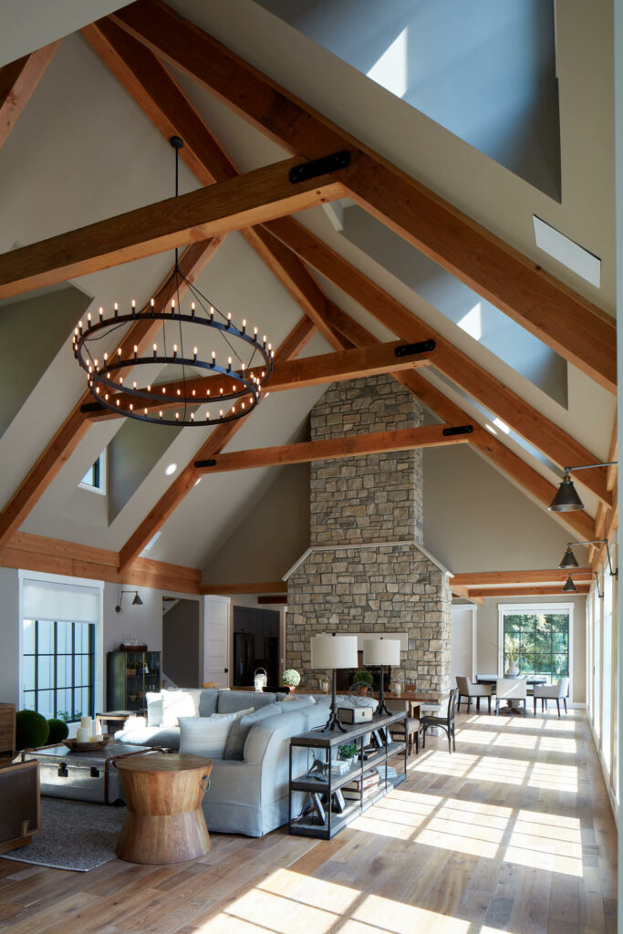 A spacious, nearly double story living room with a gabled roof and large stone fireplace, built by Curt Hofer